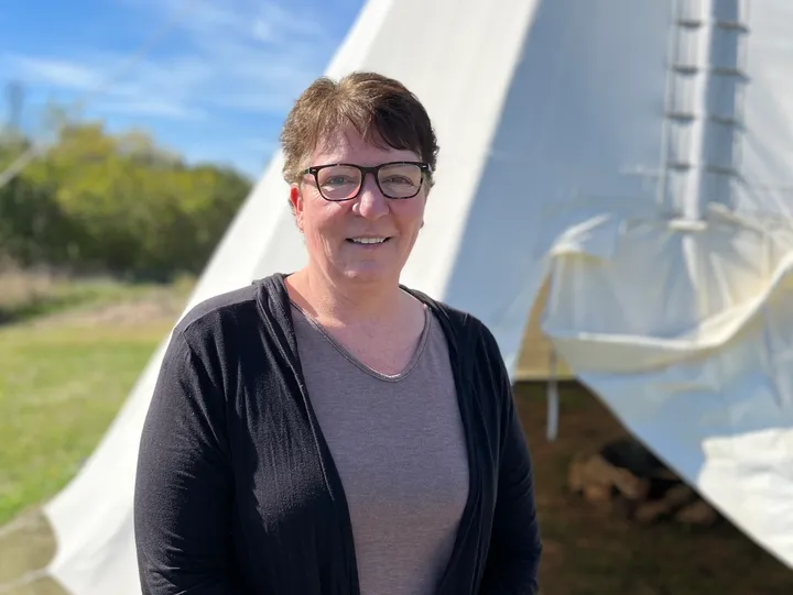 Person standing outside near a tipi.