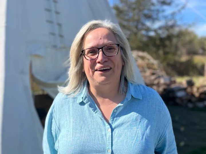 Smiling person outdoors near a white tent.