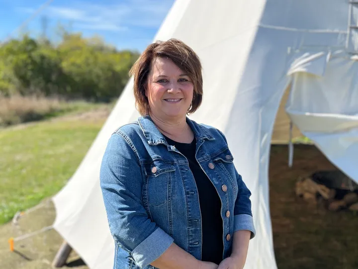 Woman smiling in front of a tipi.