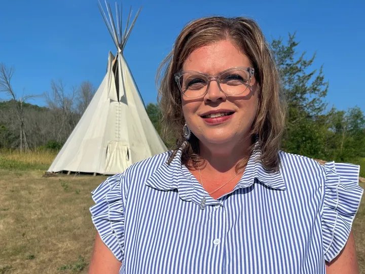 Woman smiling near a tipi outdoors.