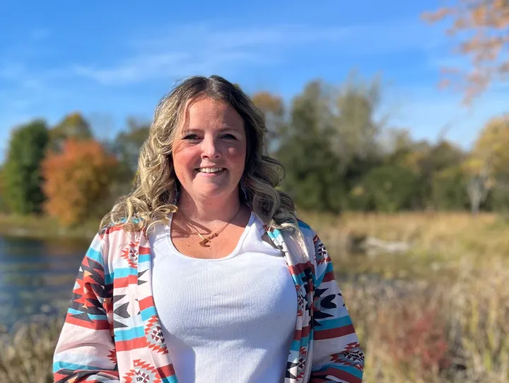 Woman smiling outdoors with autumn background.