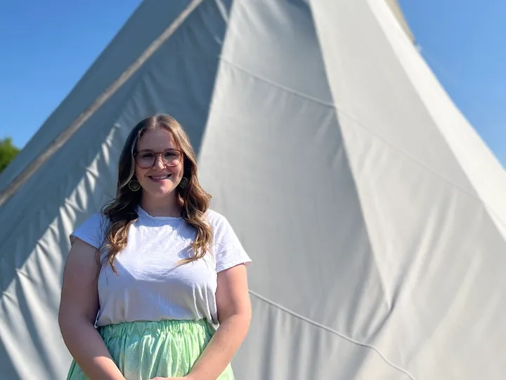 Woman smiling in front of a tipi.