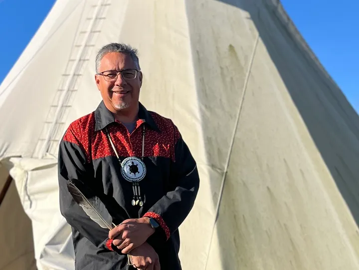 Man standing in front of a tipi.