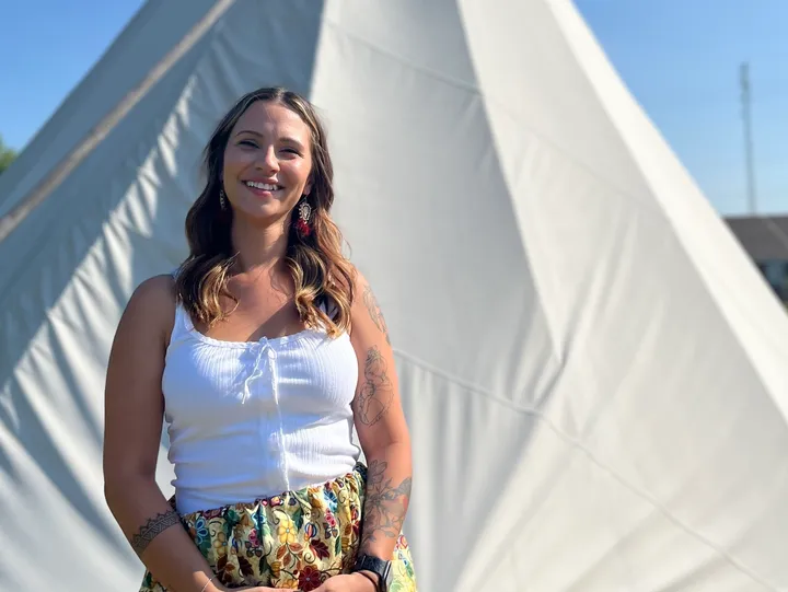 Smiling woman standing in front of teepee.