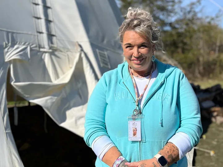 Woman standing outside near a white tent.