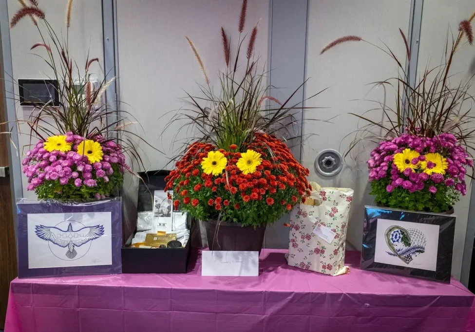 Floral arrangements and gifts on pink table.