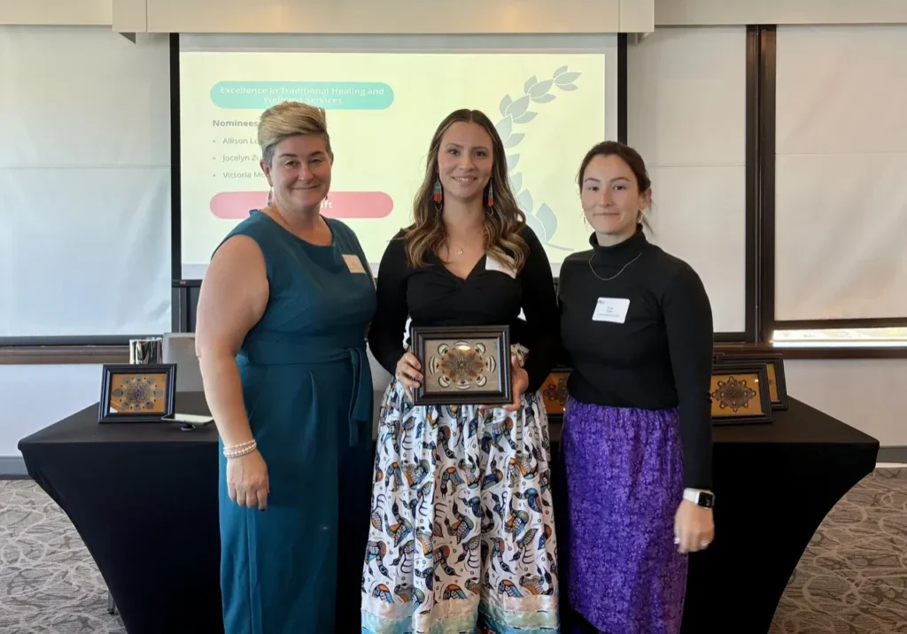 Three women holding an award at ceremony.