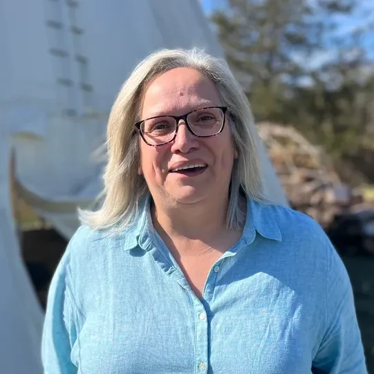 Smiling person outdoors near a white tent.