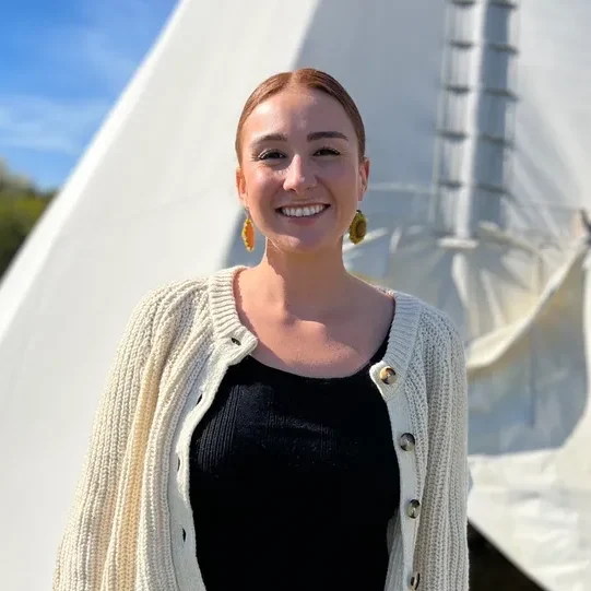 Smiling woman standing in front of tipi.