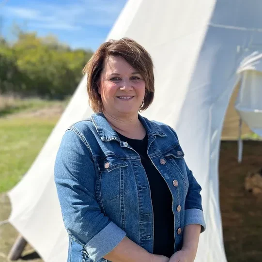 Woman smiling in front of a tipi.