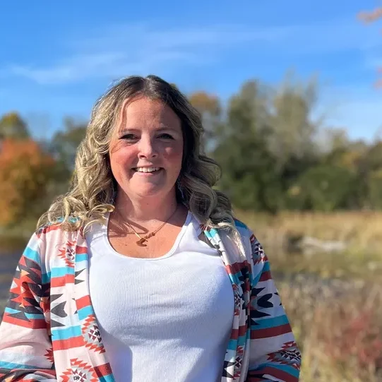 Woman smiling outdoors with autumn background.