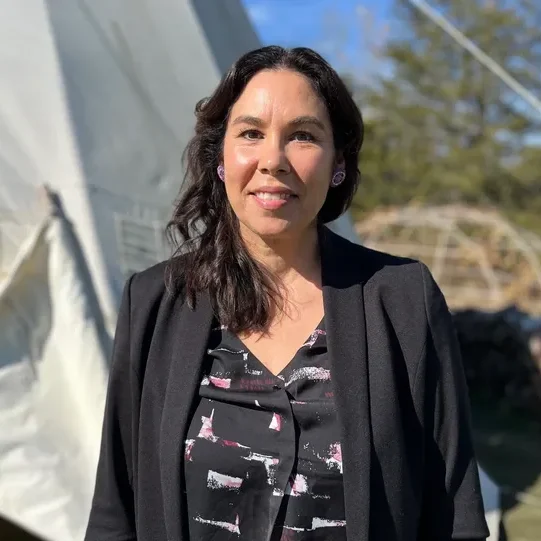 Woman standing outdoors near a white tent.