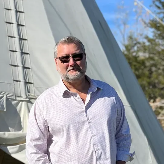 Man standing in front of a tipi.