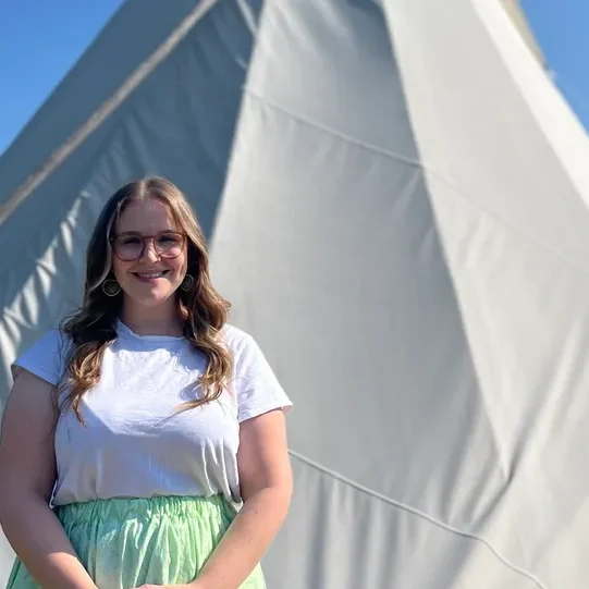 Woman smiling in front of a tipi.