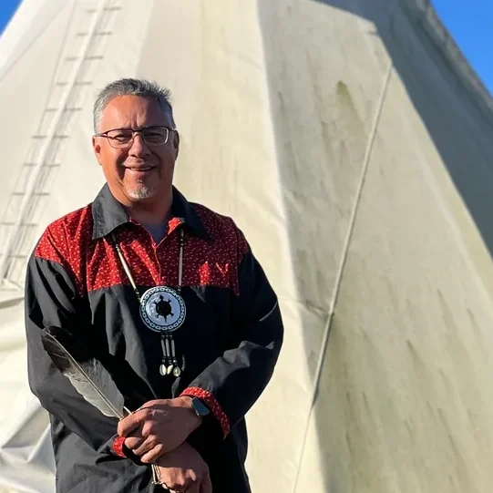 Man standing in front of a tipi.