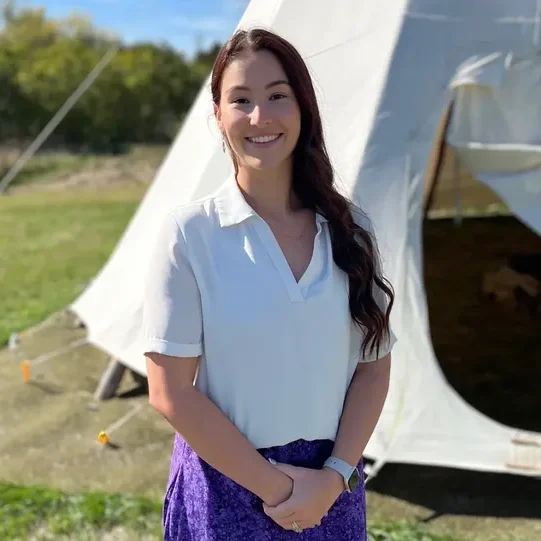 Smiling woman standing outside near tent.